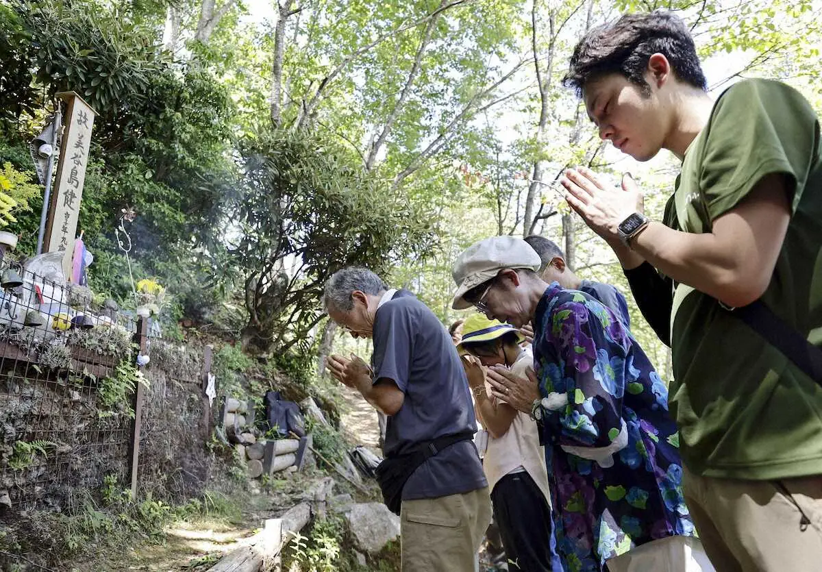 事故で亡くなった次男の墓標に手を合わせる「8・12連絡会」事務局長の美谷島邦子さん（右から2人目）ら＝12日午前、群馬県上野村