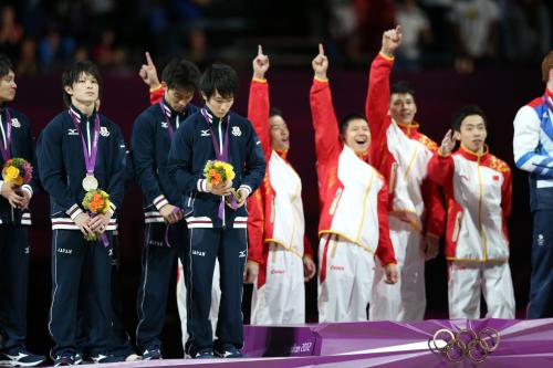 体操男子団体で金メダルに喜びを爆発させる中国チームの横で悔しげな表情を浮かべる（左から）内村航平、田中和仁、加藤凌平