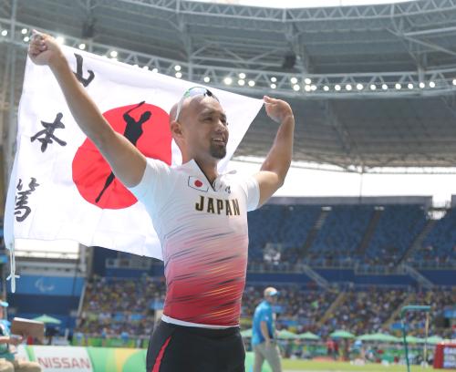 男子走り幅跳びＴ４２（切断など）決勝、銀メダルを獲得し日の丸を掲げる山本篤