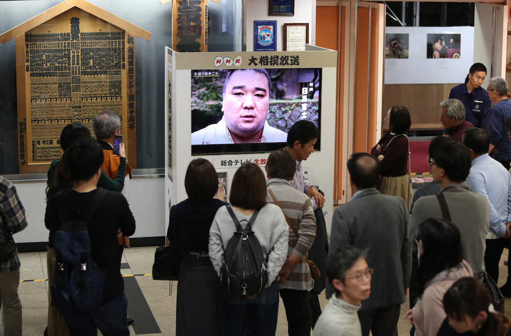 福岡国際センター内に設置されたテレビで日馬富士のニュースを見る来場者