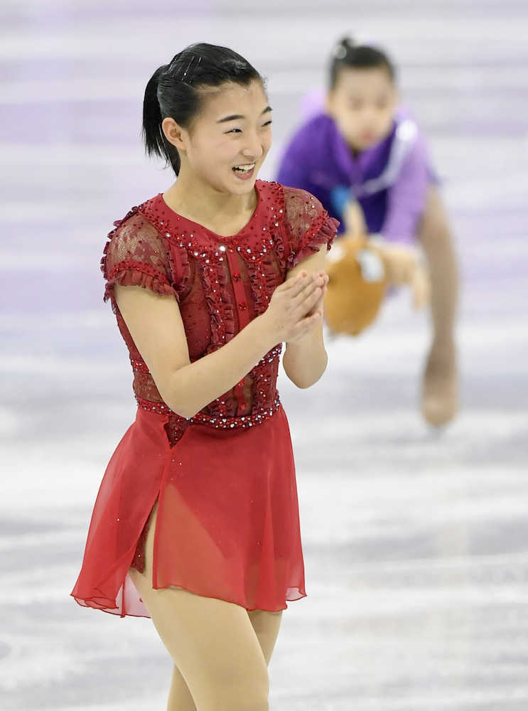 団体女子フリーの演技を終え、日本選手席に向かって、笑顔で手を合わせる坂本花織（共同）