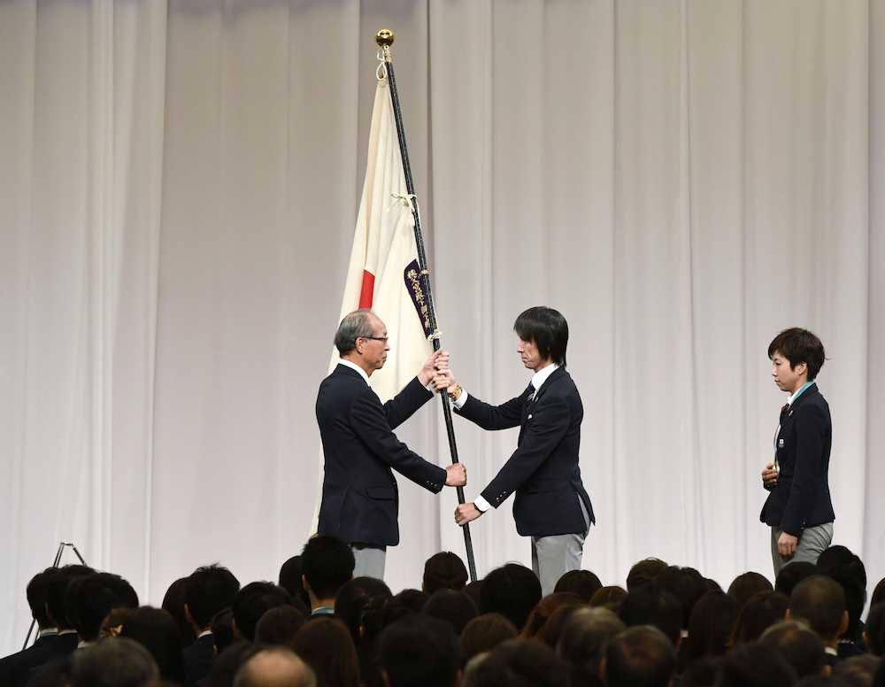 平昌五輪日本選手団の解団式で、斎藤団長（左）に団旗を手渡す葛西手。右は主将の小平