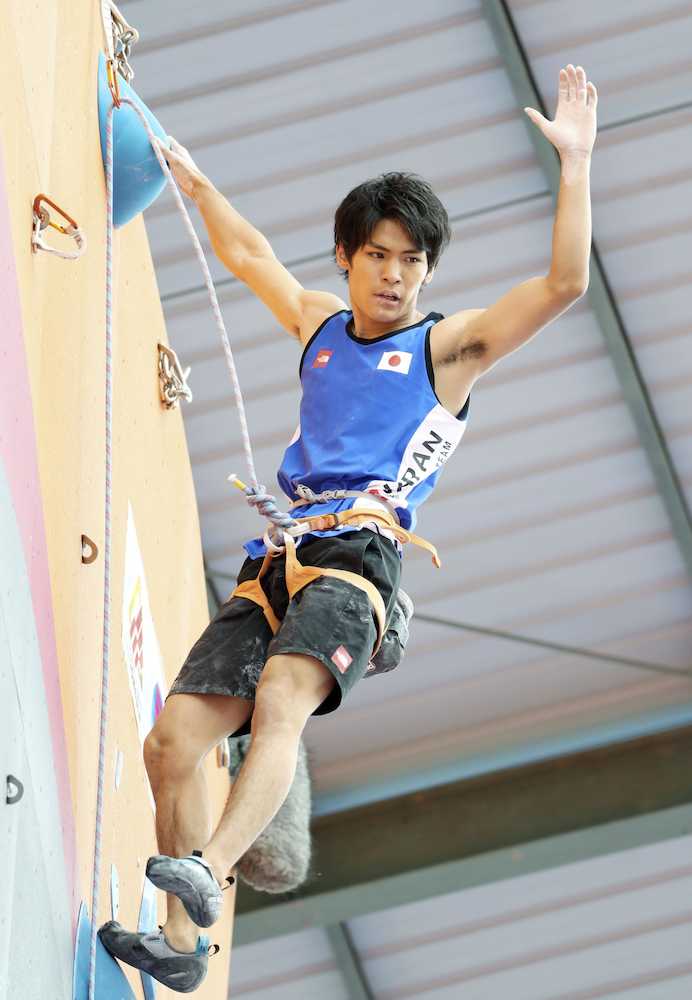 男子クライミング複合予選、リードで壁を登り切り、手を振る楢崎智