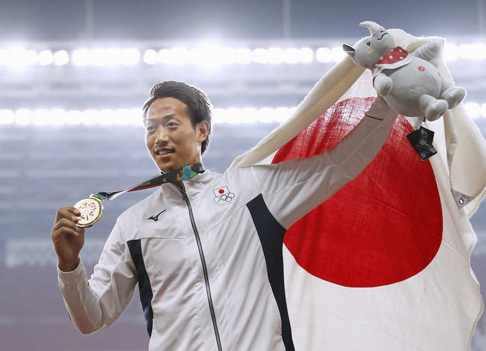男子棒高跳びで金メダルを獲得し、表彰式で日の丸を掲げる山本