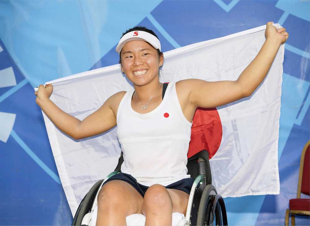 アジア・パラ車いすテニス女子シングルスで優勝し笑顔で日の丸を掲げる上地
