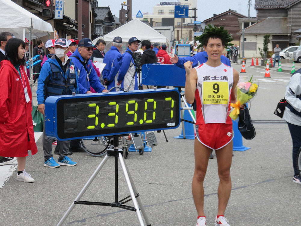 50キロ競歩の日本新記録をマークした鈴木雄介は速報計時版の前でポーズ（撮影・中出　健太郎）