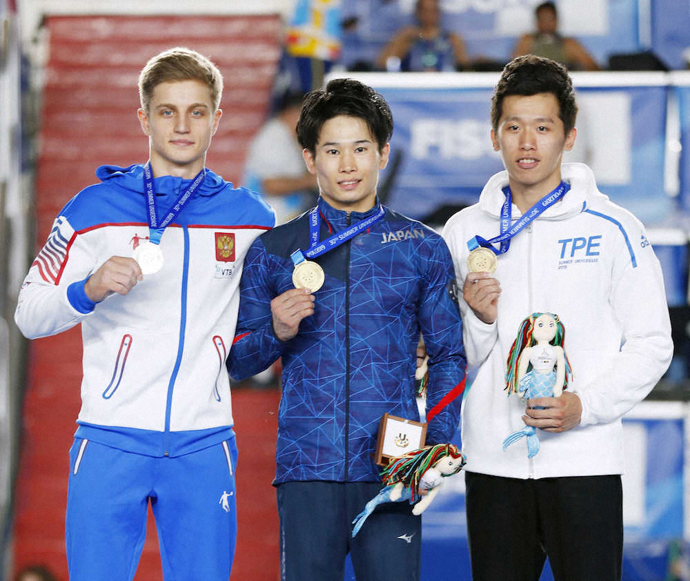 体操男子個人総合で優勝し、表彰台で金メダルを手にする萱（中央）