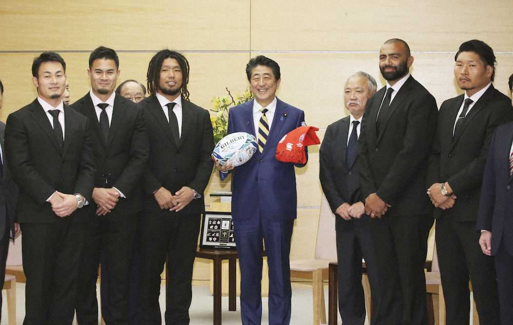 安倍首相（中央）と面会し、記念のラグビーボールとTシャツを贈ったラグビーW杯日本代表のリーチ・マイケル選手（右から2人目）ら