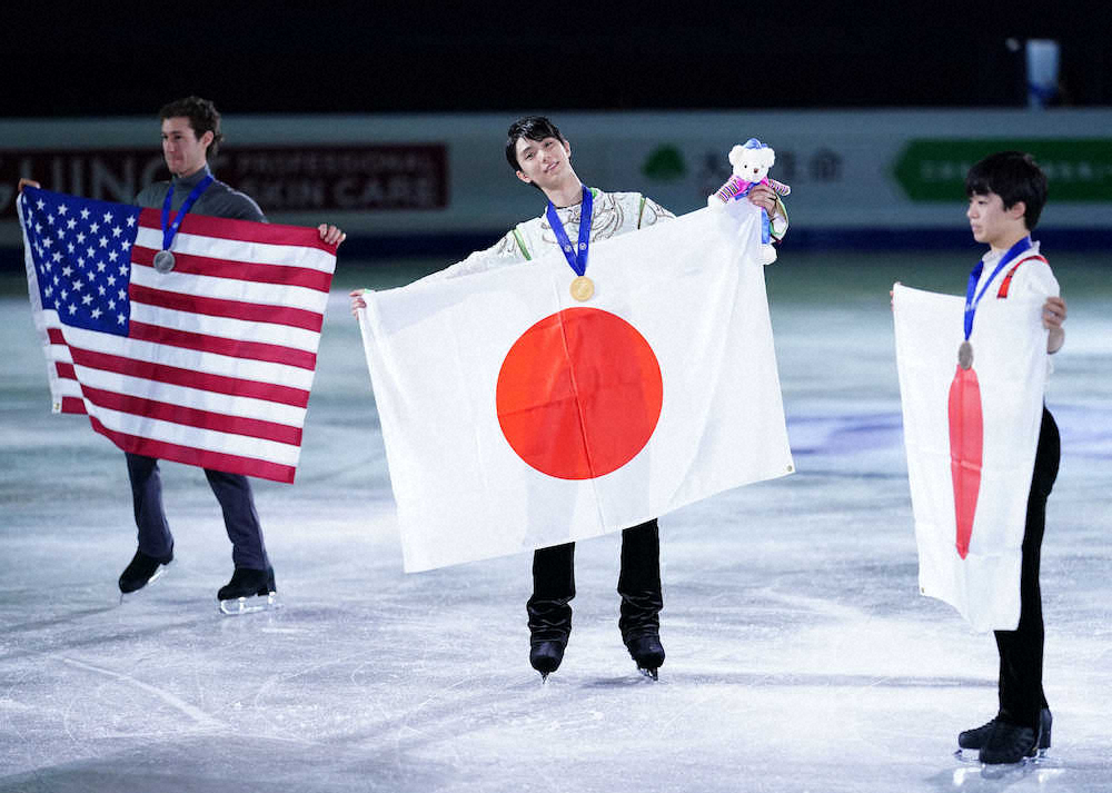 表彰式で国旗を広げる（左から）ジェイソン・ブラウン、羽生結弦、鍵山優真（撮影・小海途　良幹）