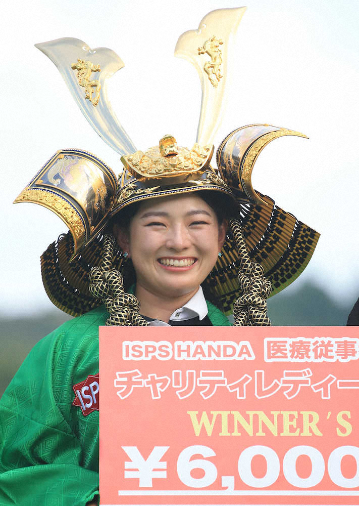 ＜ISPS　HANDAチャリティーレディース＞優勝した吉川桃はチャンピオン羽織と兜を身につけ笑顔を見せる（撮影・西尾　大助）　