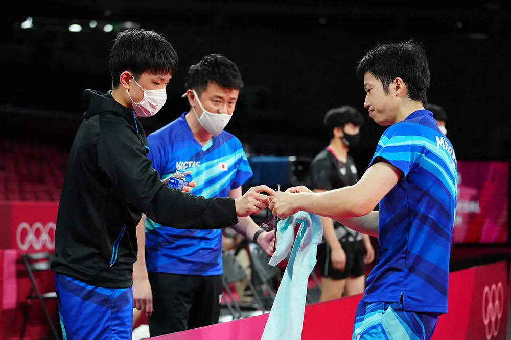 東京五輪卓球男子団体３位決定戦で、水谷隼（右）の眼鏡を受け取る張本智和（撮影・会津智海）