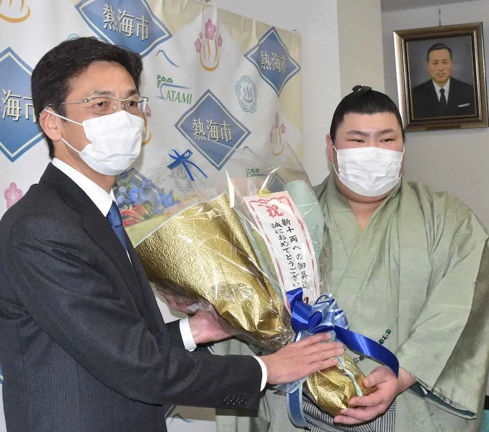 熱海市の斉藤市長（左）から花束を手渡される熱海富士