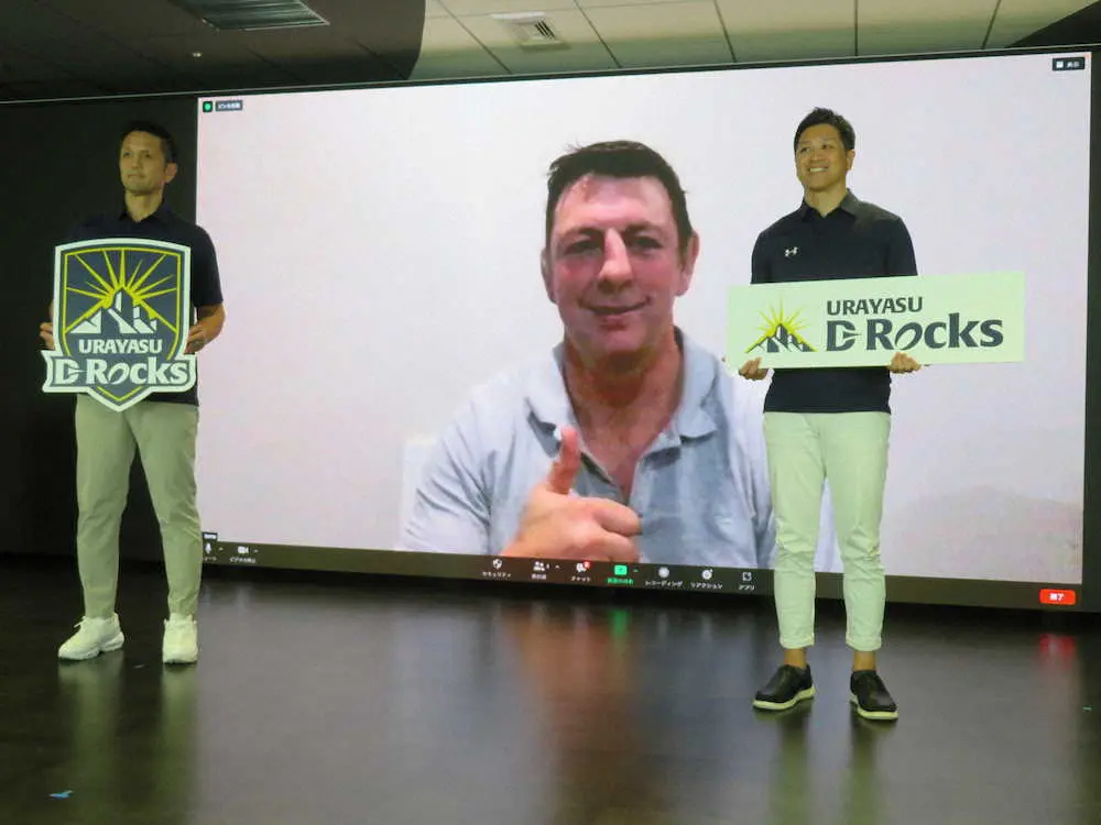 NTTグループのラグビー新チーム「浦安D－Rocks」の会見に出席した下沖正博社長（左）、内山浩文GM（右）と、スコッド入りしたトンプソン・ルーク（画面）