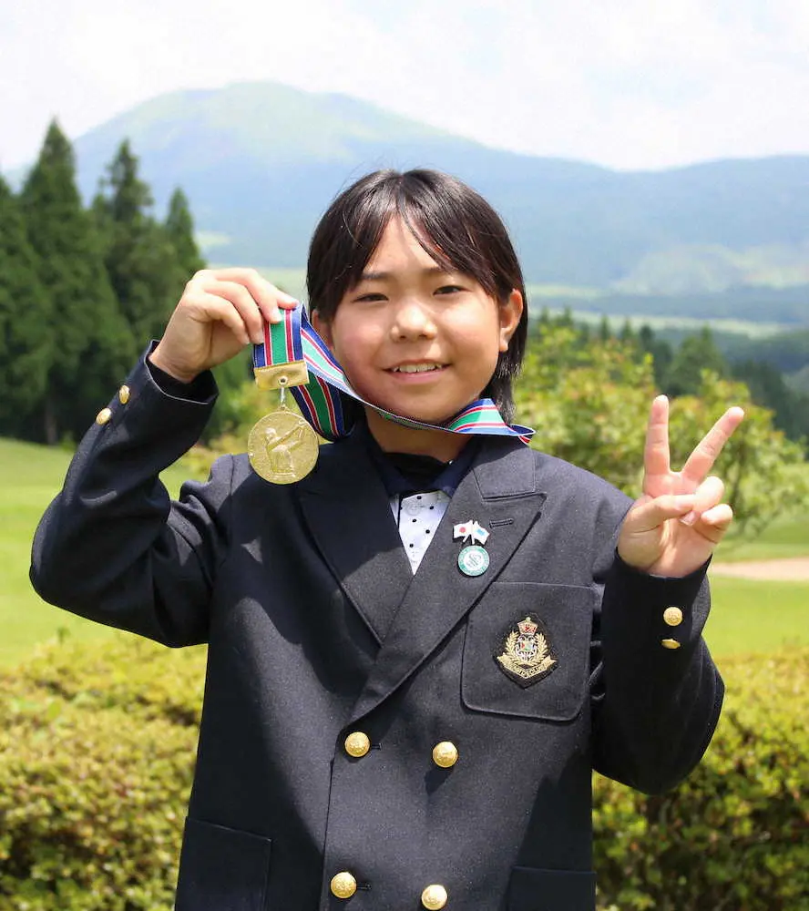 女子優勝の呉屋は阿蘇を背にメダルを掲げて笑顔