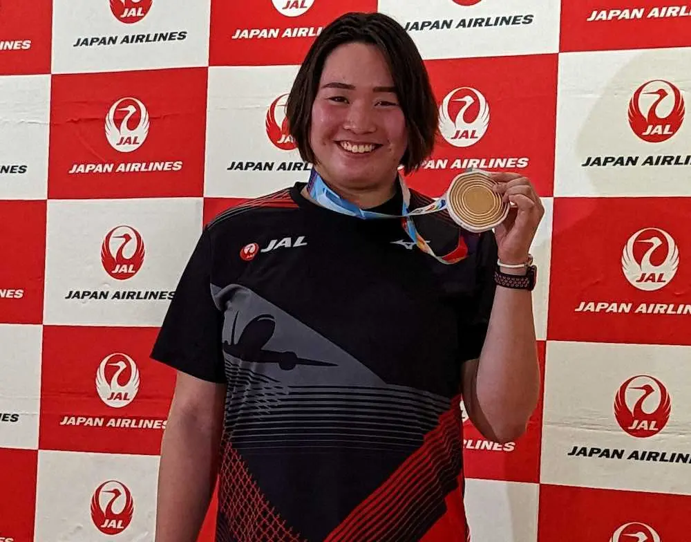 羽田空港に帰国した女子やり投げの北口は、世界選手権の銅メダルを手に笑顔