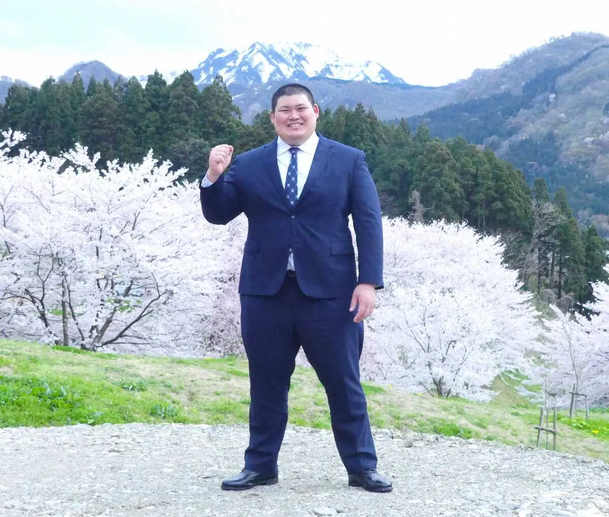 新潟県糸魚川市の海洋高で、桜と山をバックにポーズを取る中村泰輝（撮影・前川　晋作）