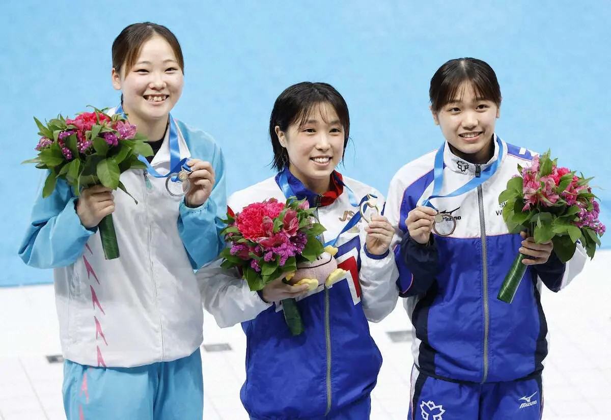 　女子高飛び込みで優勝し、メダルを掲げる荒井祭里（中央）。左は2位の山崎佳蓮＝東京アクアティクスセンター