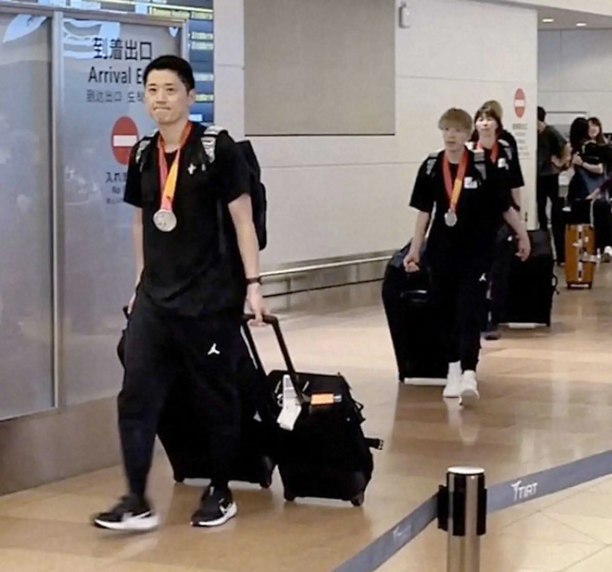 帰国したバスケットボール女子日本代表の恩塚監督（左端）ら＝3日、羽田空港