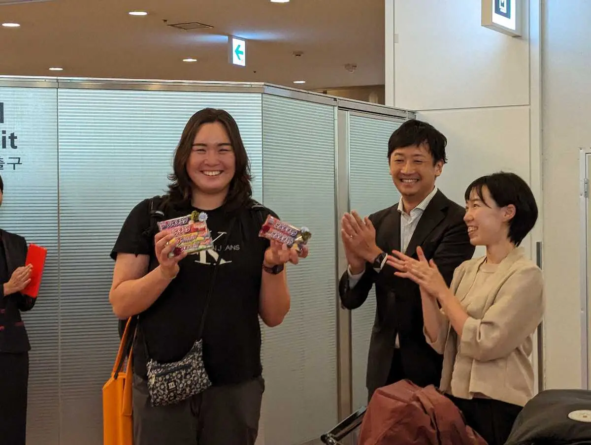 羽田空港に帰国しハイチュウをプレゼントされ笑顔の北口榛花（左）