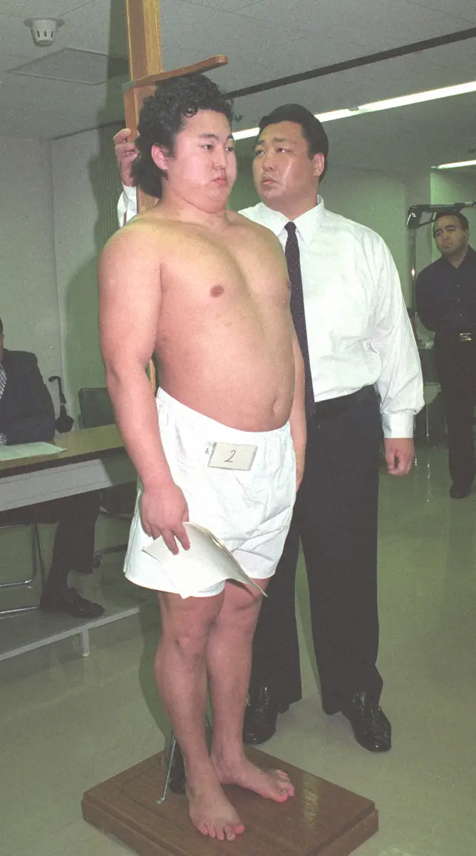 1990年5月、　大相撲新弟子検査で頭をこん棒で殴りコブを作って合格した長尾（のちの舞の海）。身長を計るのは北の湖親方