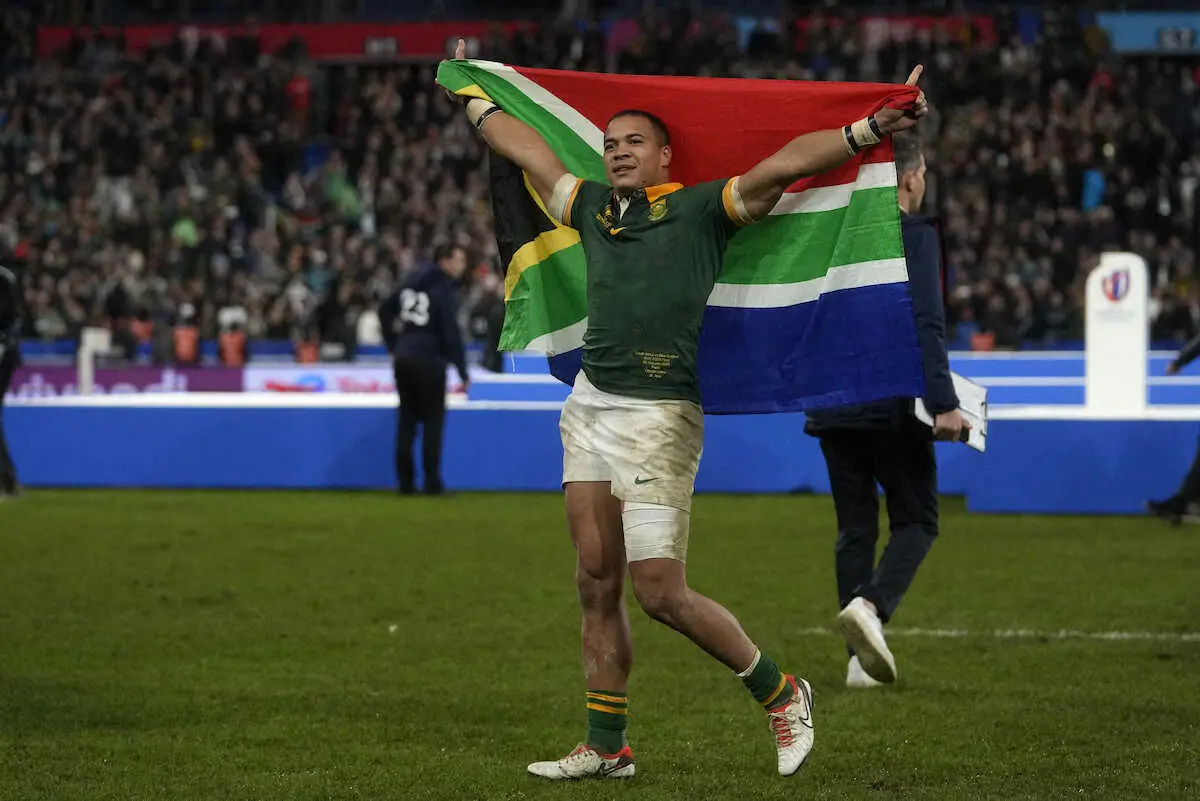 ＜ニュージーランド・南アフリカ＞連覇を達成し、笑顔で国旗を掲げる南アフリカのコルビ（AP）