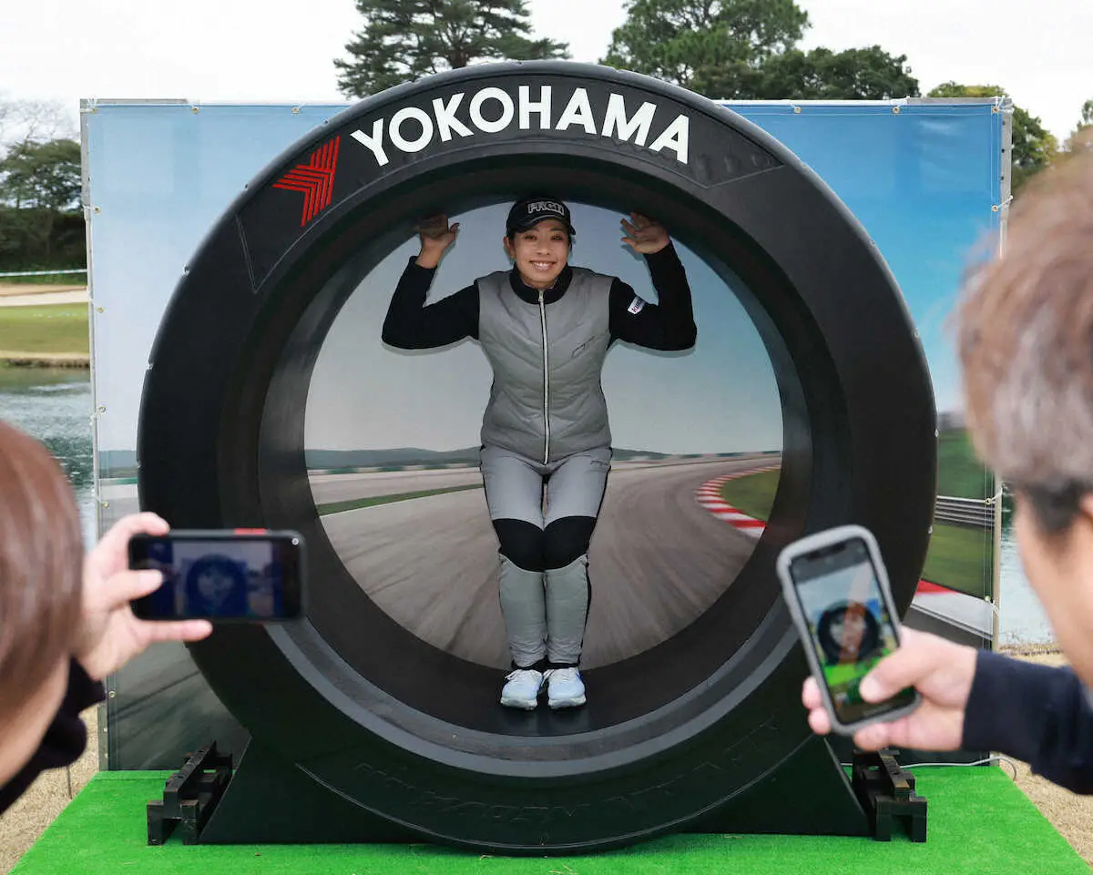2メートルの大型タイヤで記念撮影するPRGRのホステス森田理香子（撮影・井垣　忠夫）