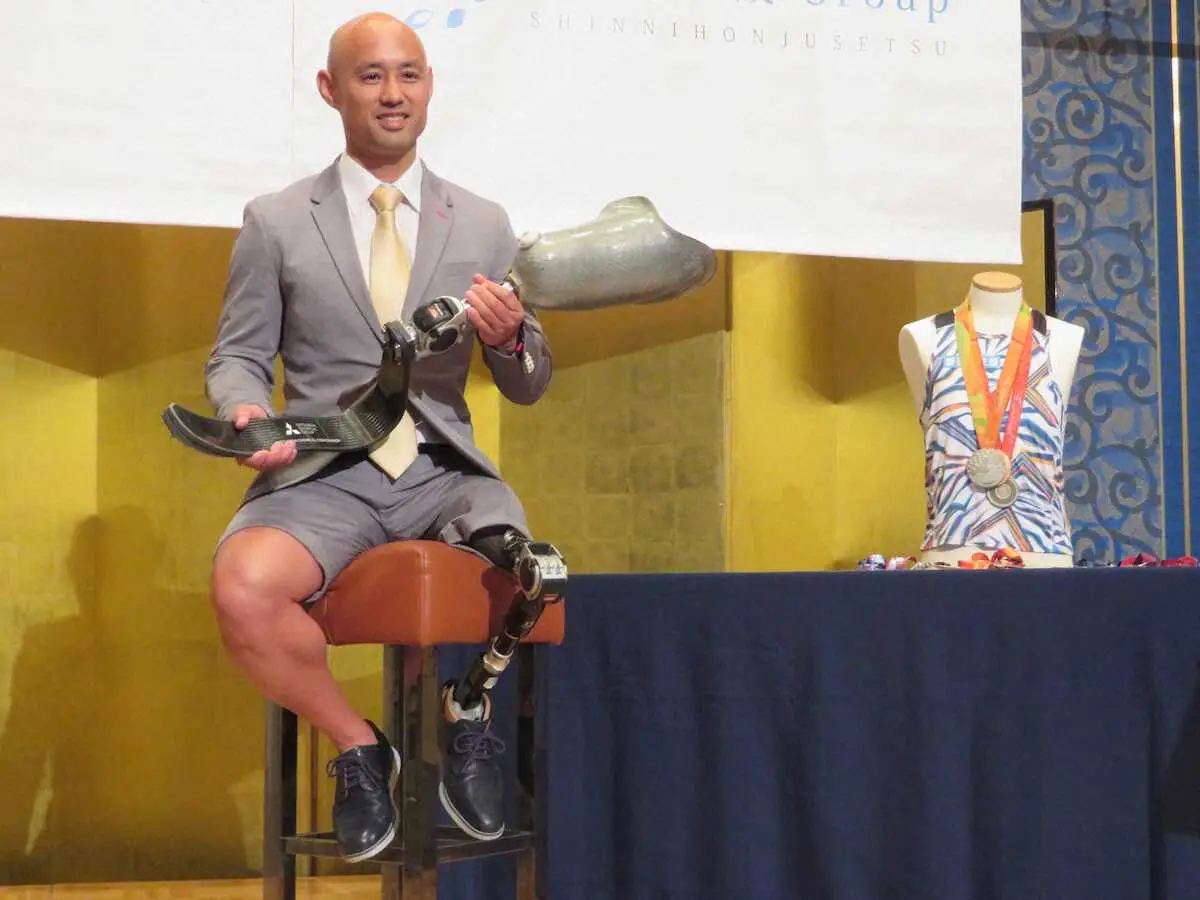 義足とポーズを取る山本篤、右にはパラリンピックで獲得した3つのメダルが輝く（神戸市内のホテルで）