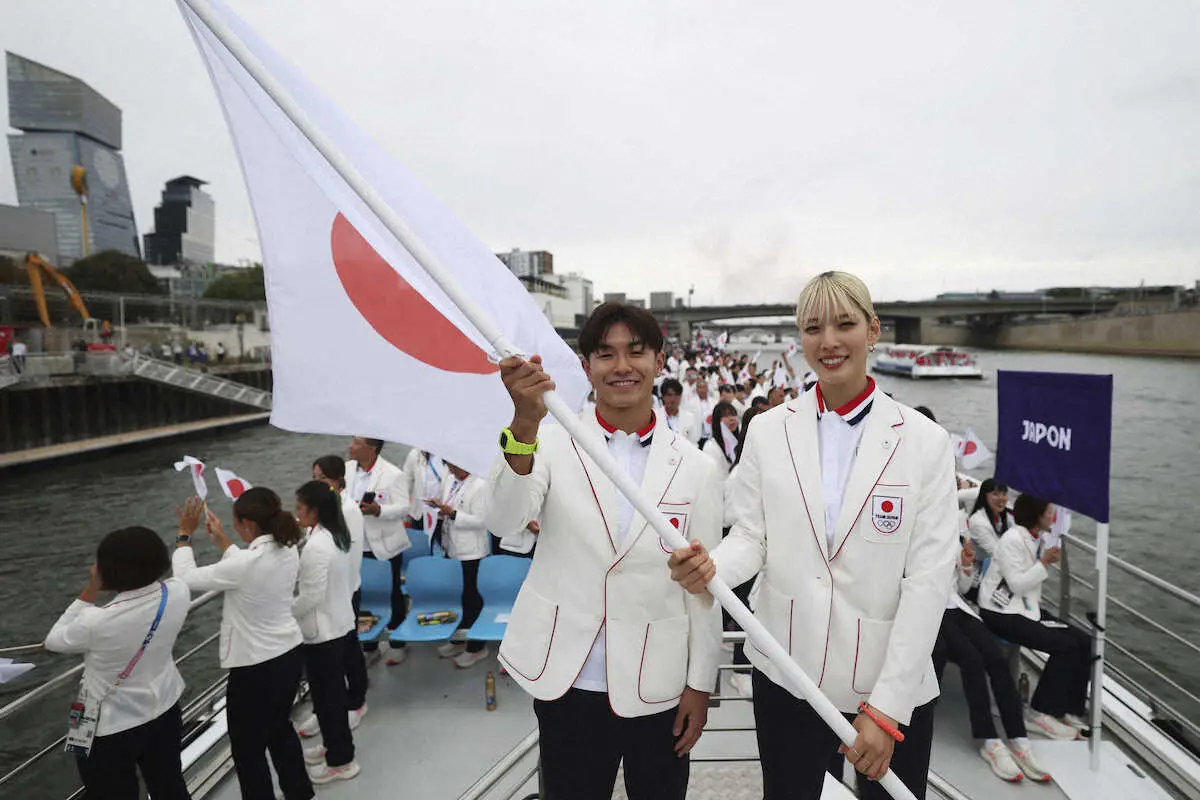 チームジャパンの旗手であるシゲキックスと江村美咲がパリ五輪開会式で、セーヌ川を航行する船の上で日本国旗を掲げて記念撮影（AP)