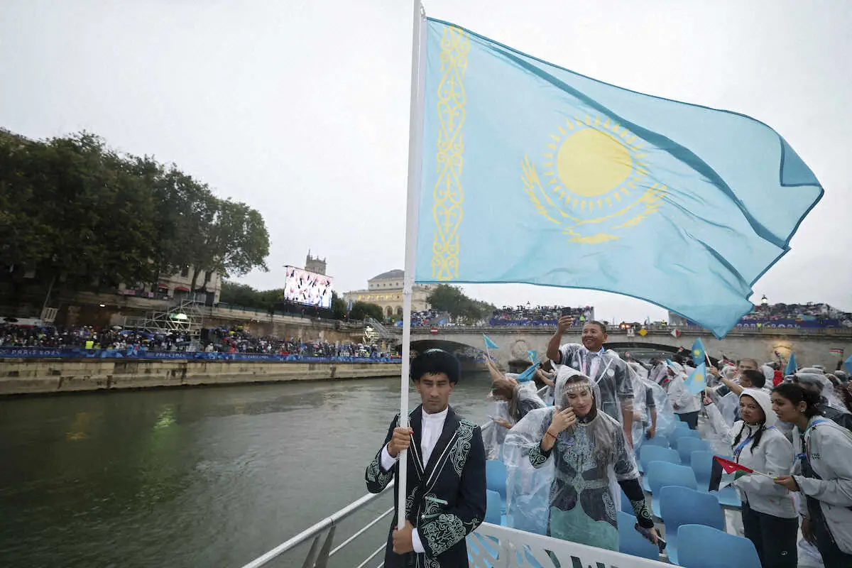 パリ五輪開会式のセーヌ川の水上パレードに参加したカザフスタンの旗手を務めるボクシングのアスランベク・シムベルゲノフと陸上のオルガ・サフロノワ（AP）