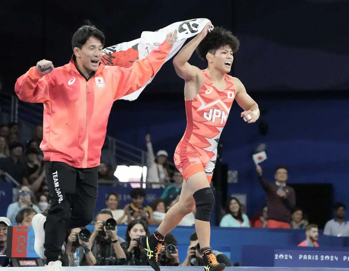 ＜パリ五輪・男子フリースタイル65キロ級決勝＞金メダルを獲得した日の丸を手に喜ぶ清岡（右）（撮影・岡田　丈靖）